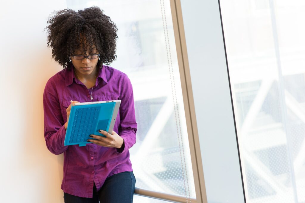 woman leaning up against wall using an ipad with a blue case