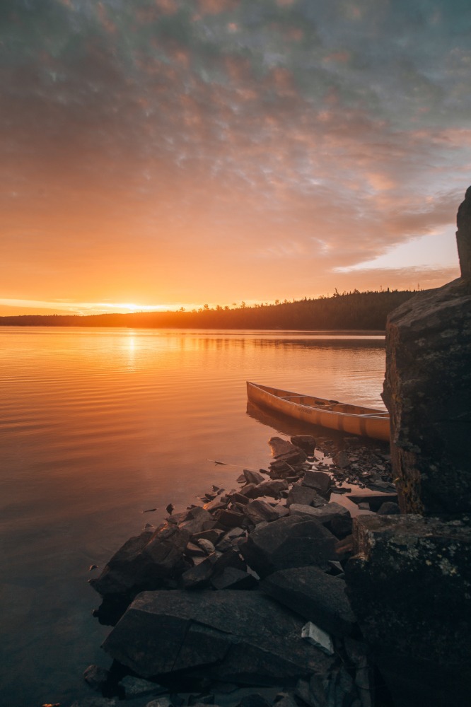 canoe resting on the rocky shore of the boundary waters at sunset